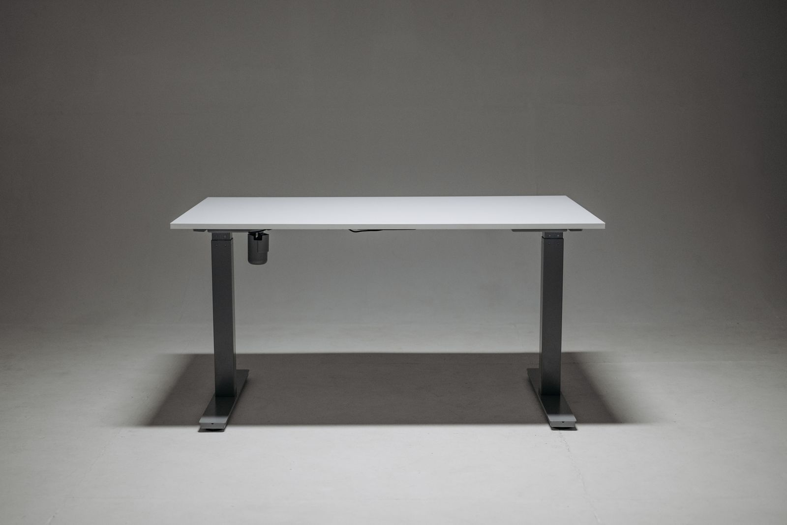 White adjustable-height standing desk set up in a bright home office
