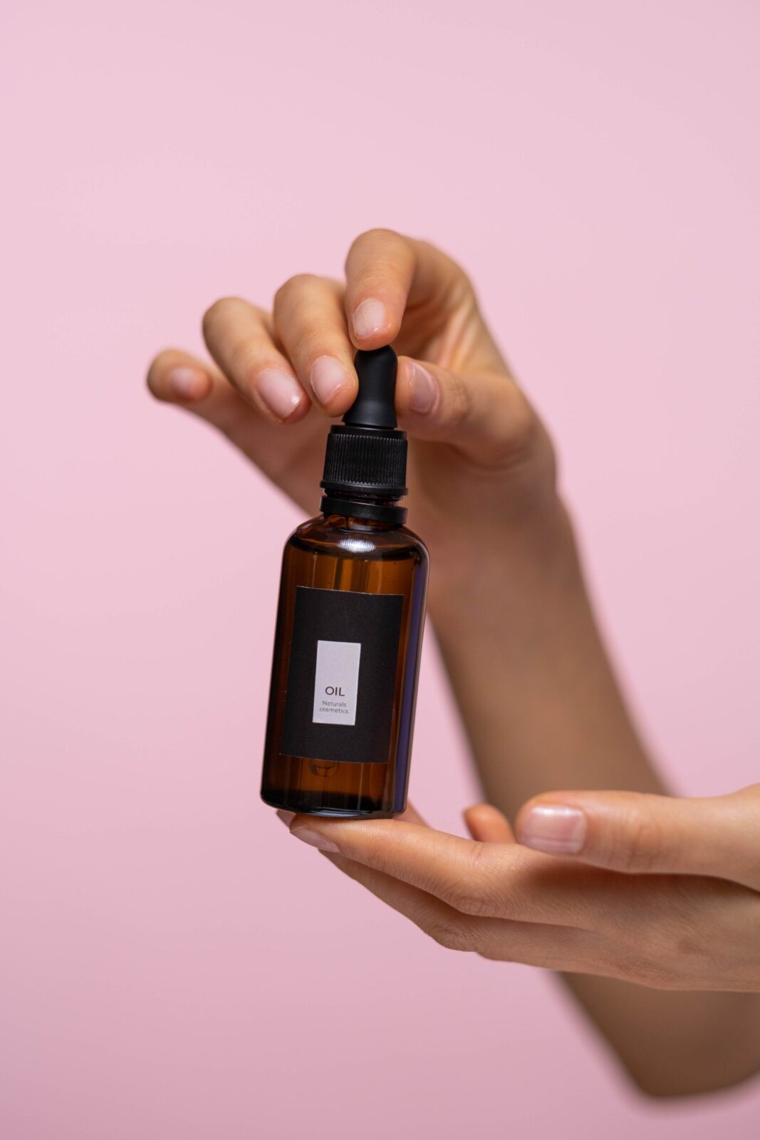 Hand holding a dark amber glass bottle of vitamin C serum