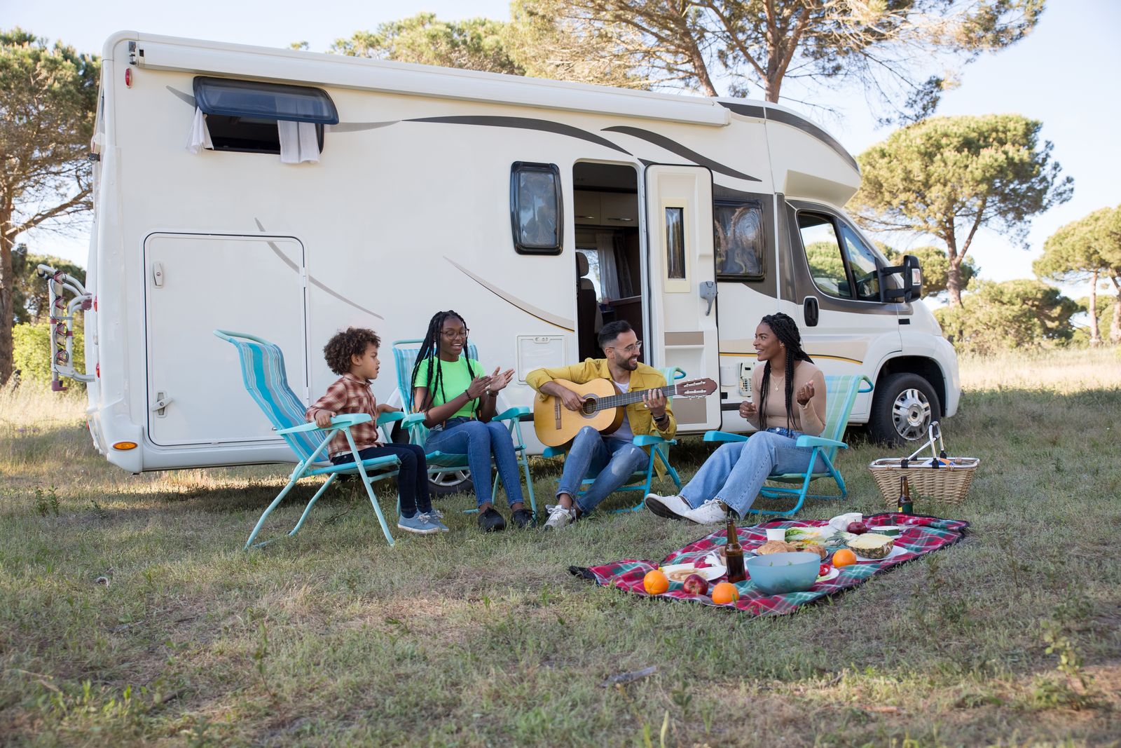 Family sitting in blue and white folding camping chairs at a campsite