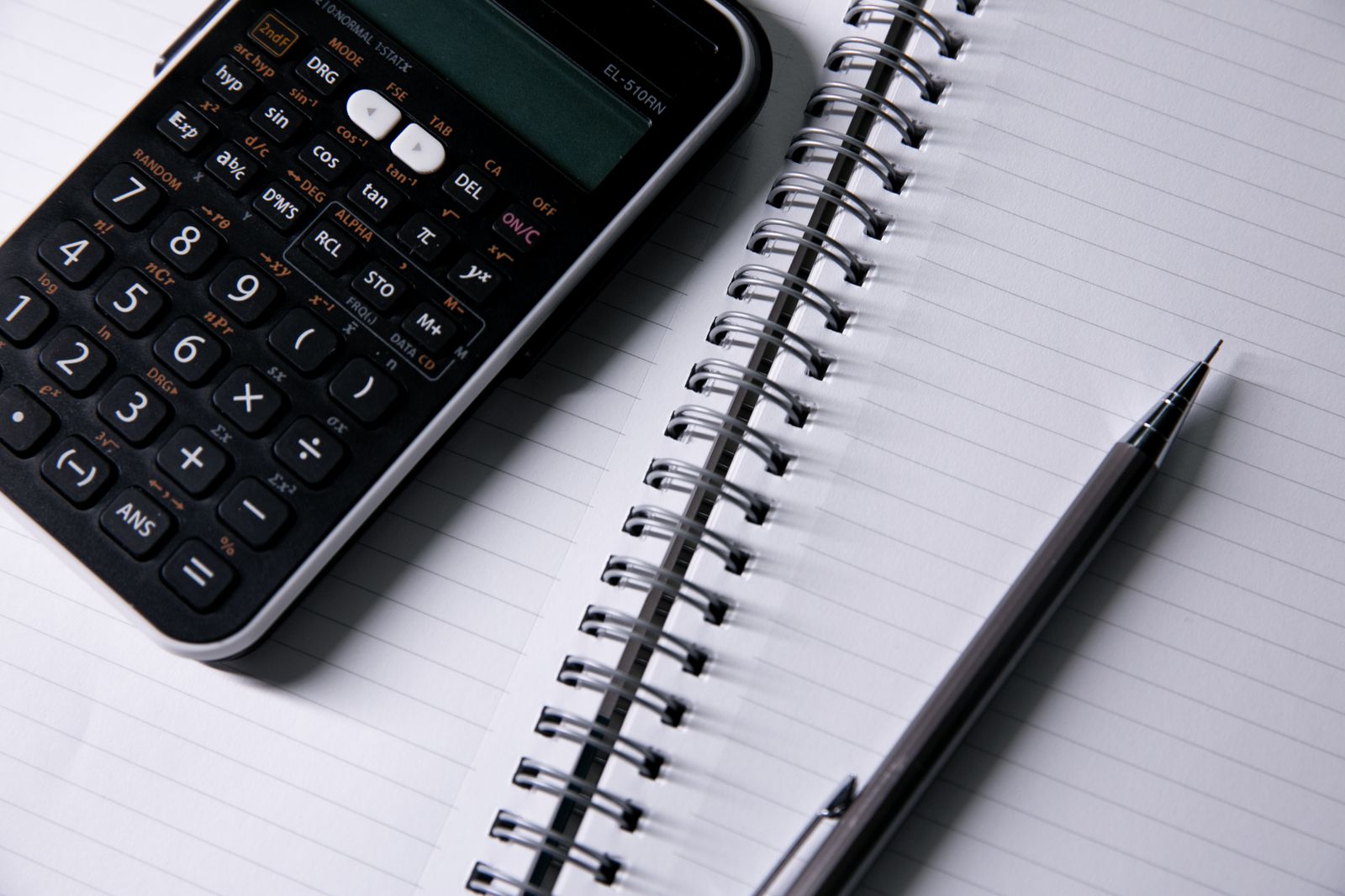 Close-up of an open notebook, a calculator, and a pen