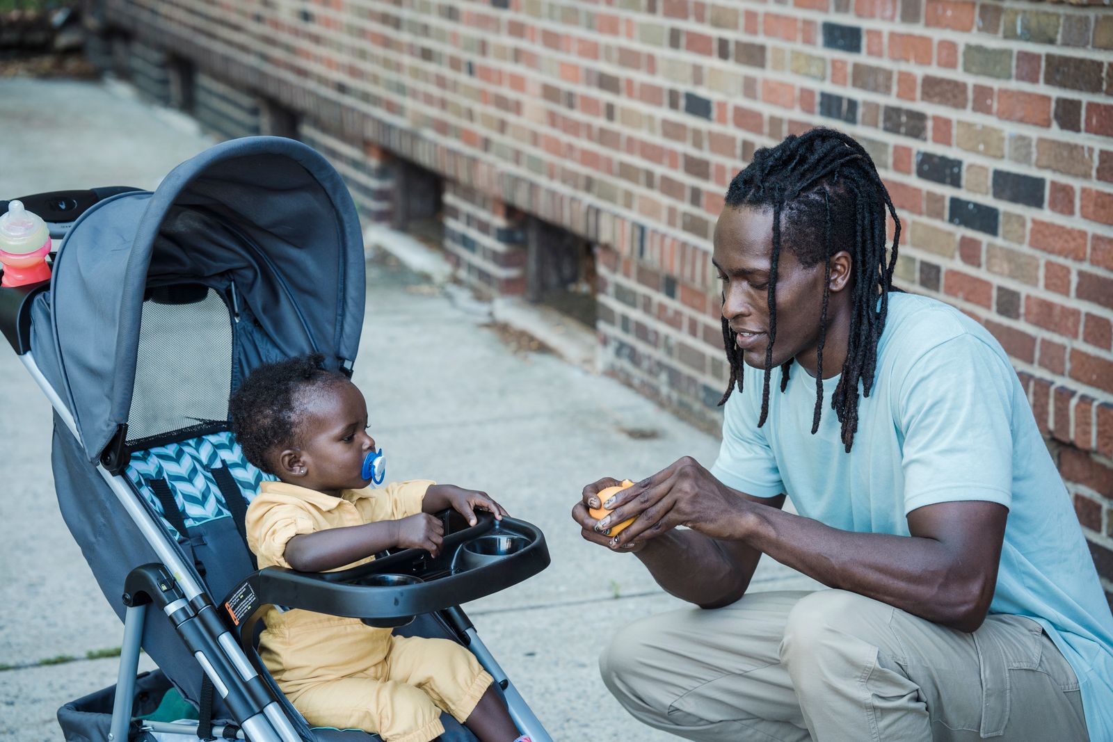 A parent beside a child in a baby stroller during an outing