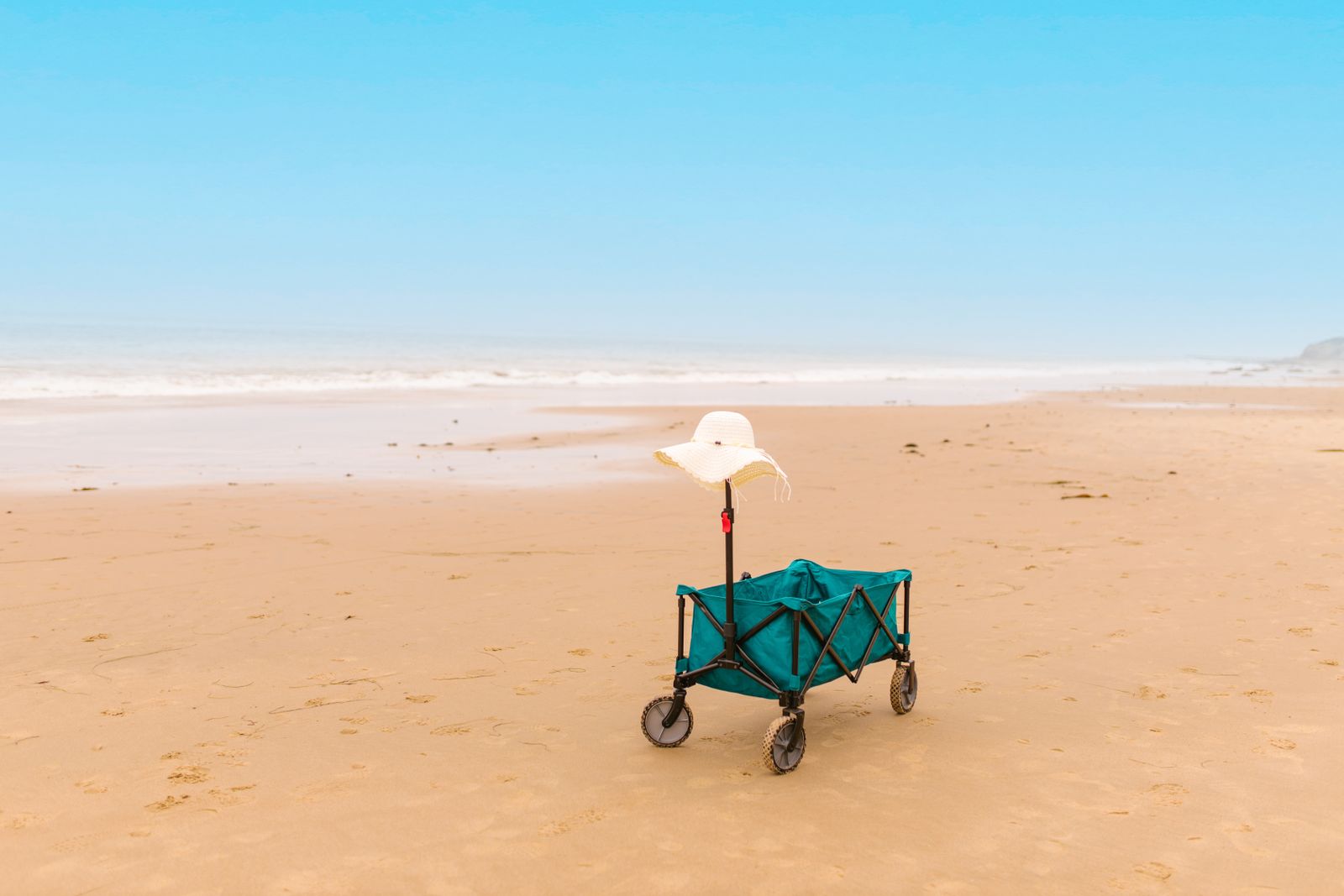 Beach wagon loaded with chairs, cooler, and umbrella on the sand