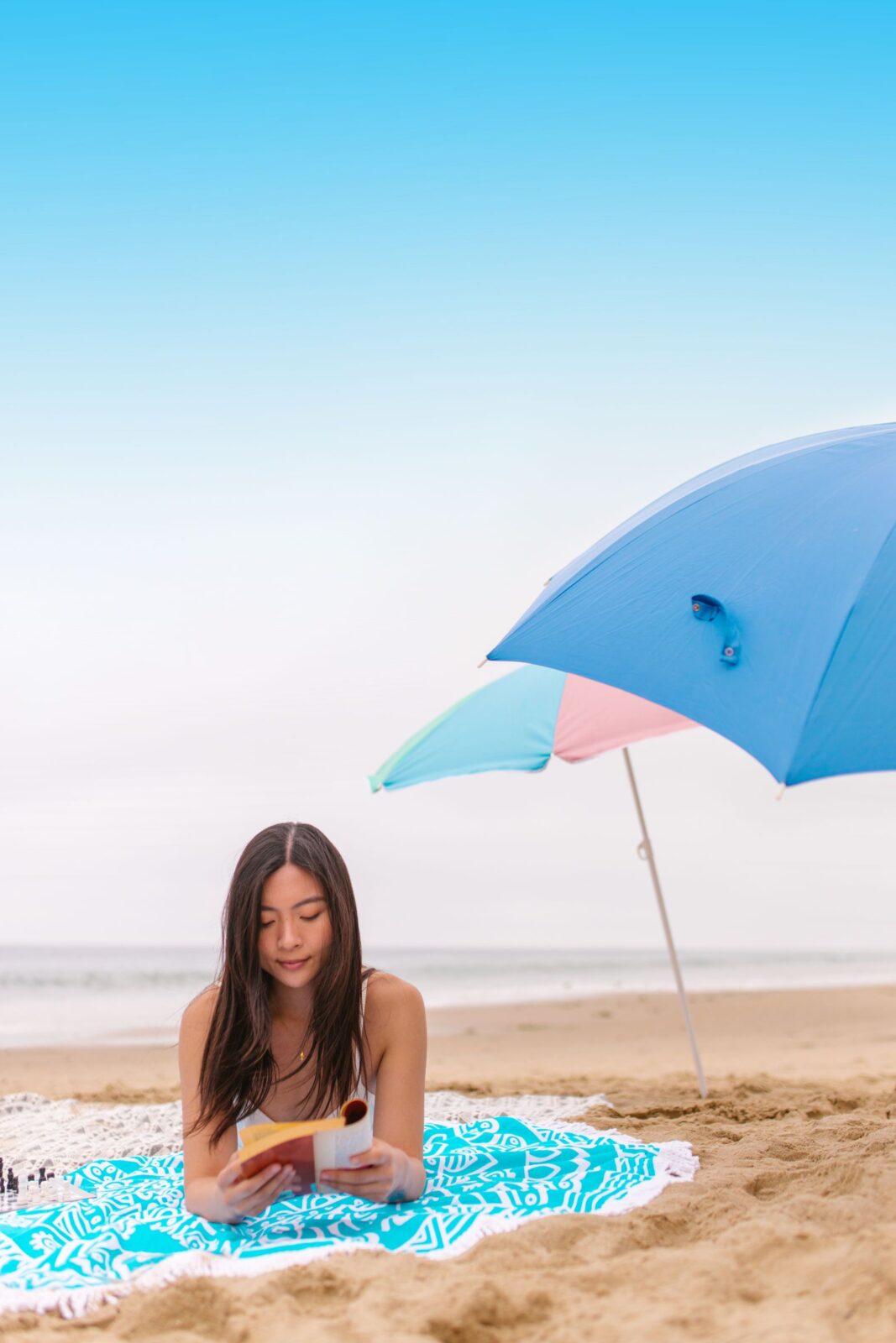 Woman relaxing under a beach umbrella on a sunny shoreline