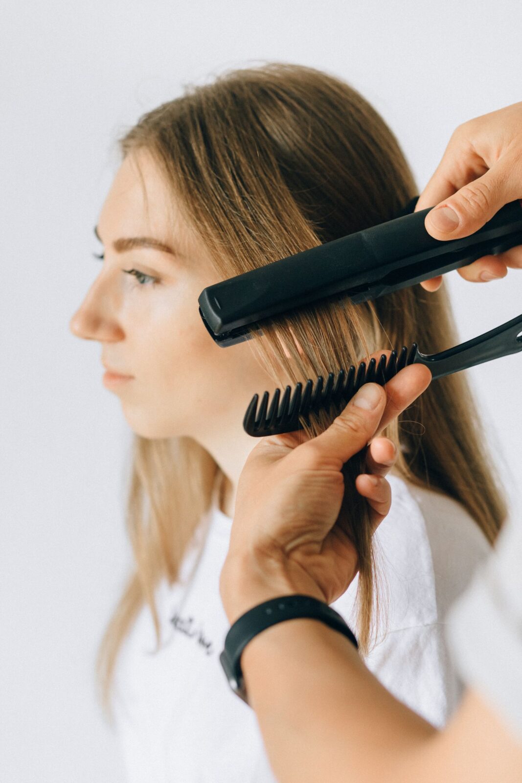 A woman with bouncy curls styling her hair with a curling tool