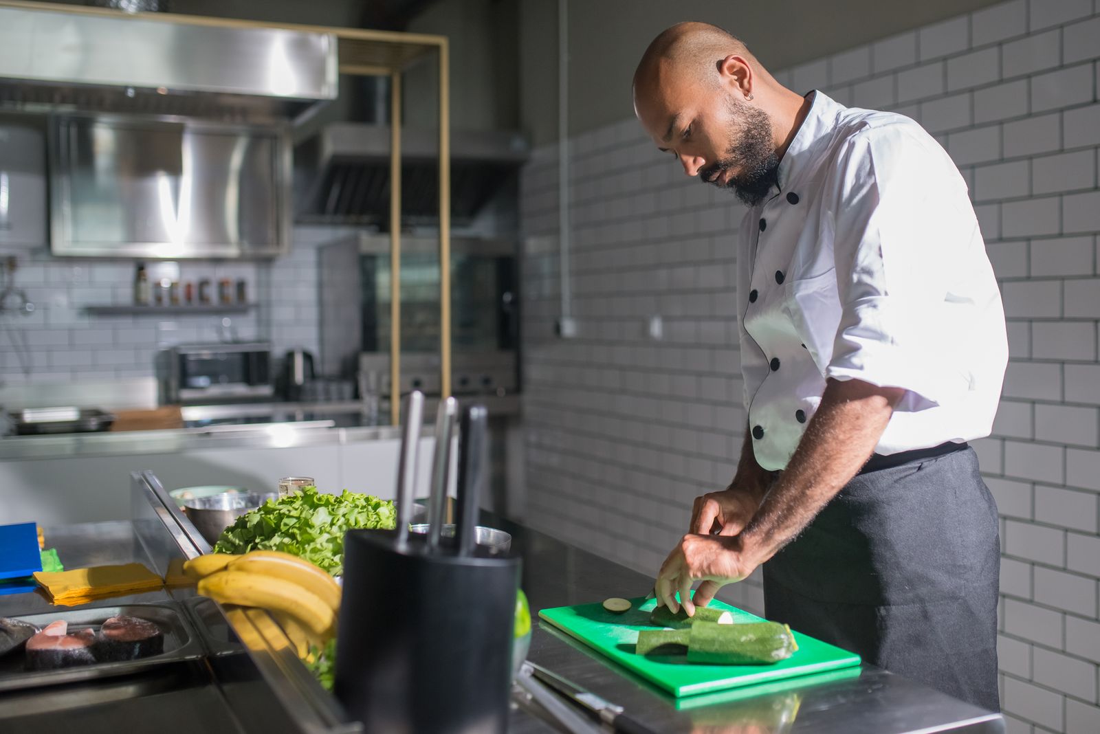 A chef practicing knife skills cutting vegetables on a board