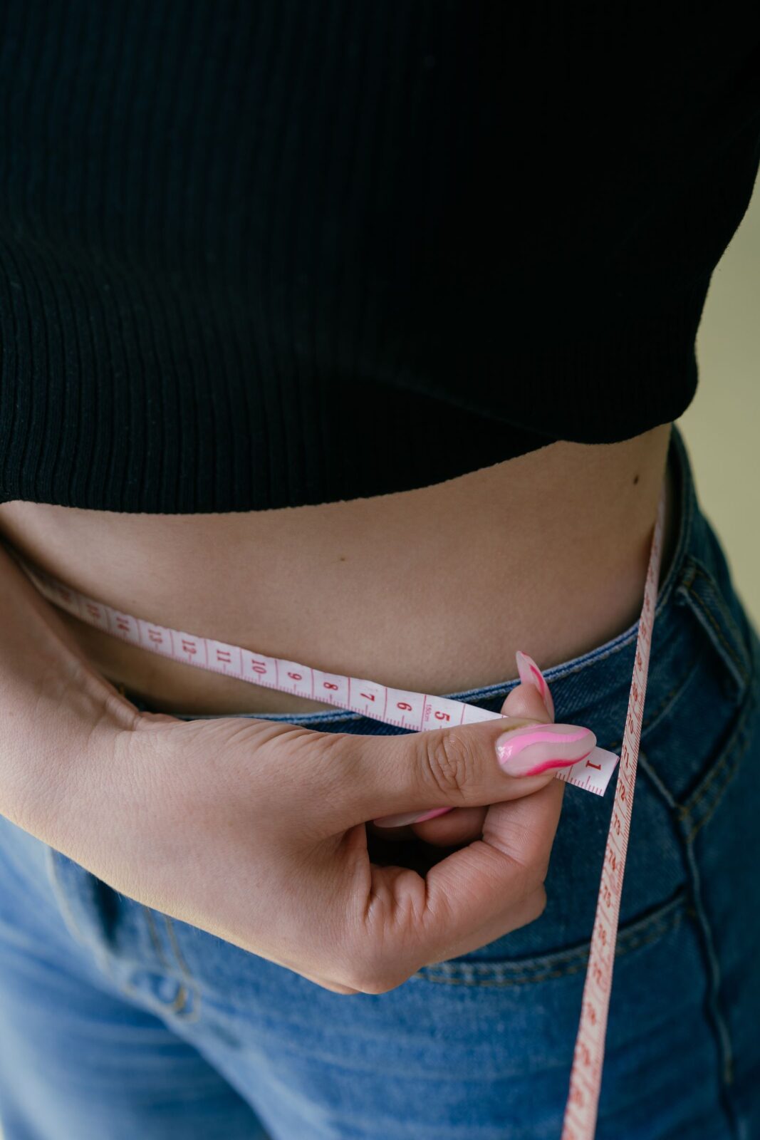 A person measuring their waist with a tape measure
