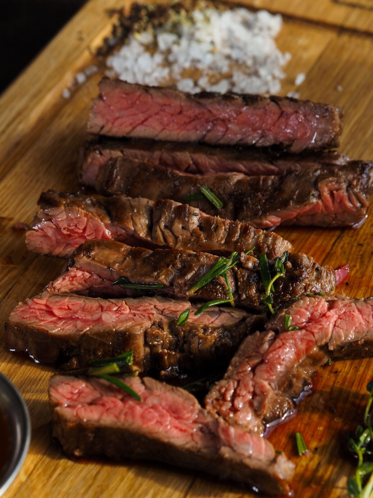 Edge-to-edge medium-rare steak sliced on a wooden board