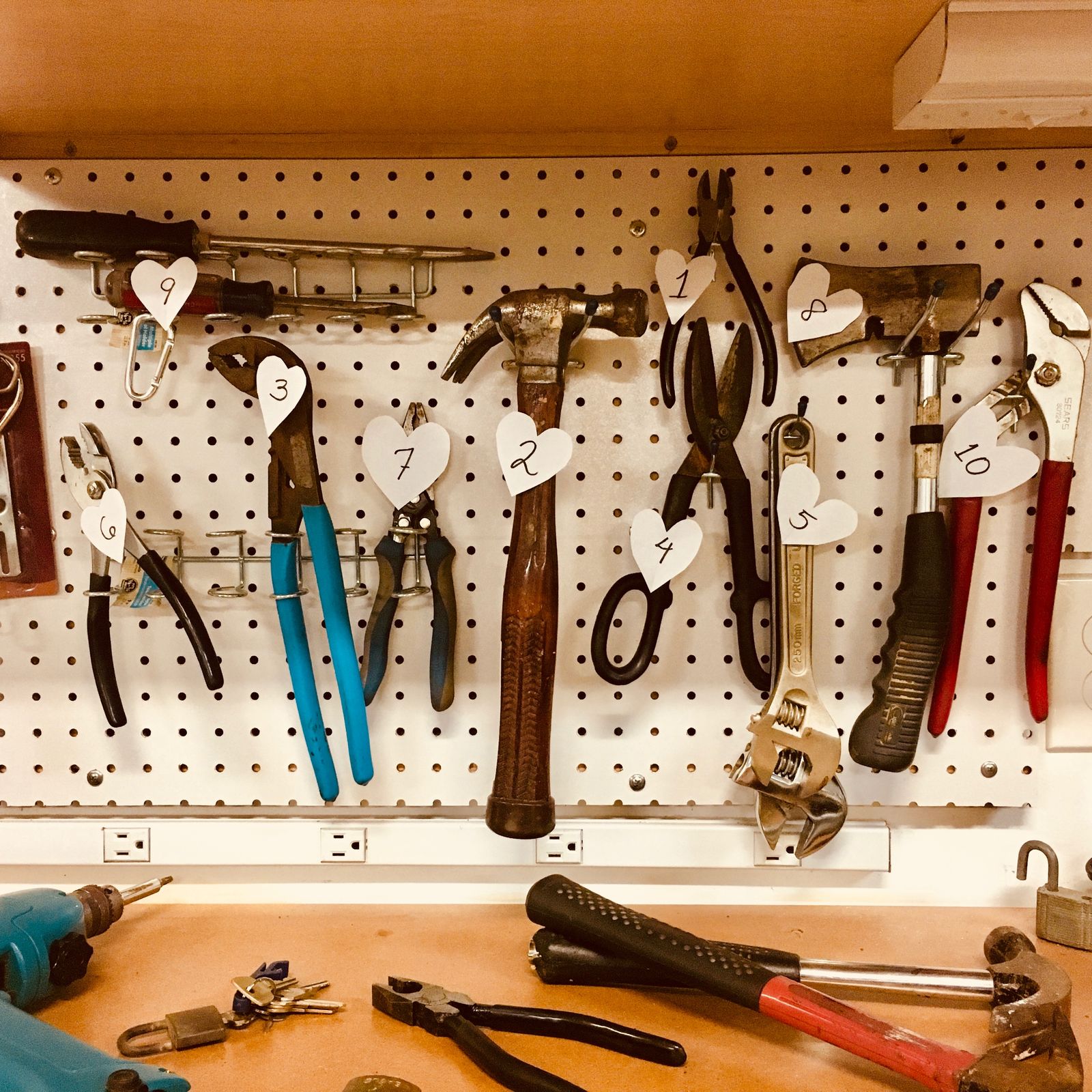 Hand tools hanging in rows on a workshop wall storage system
