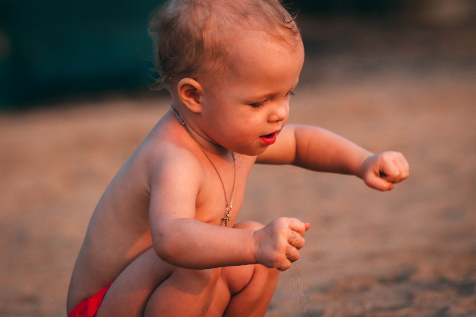 Toddler scooping and exploring sand with small hands