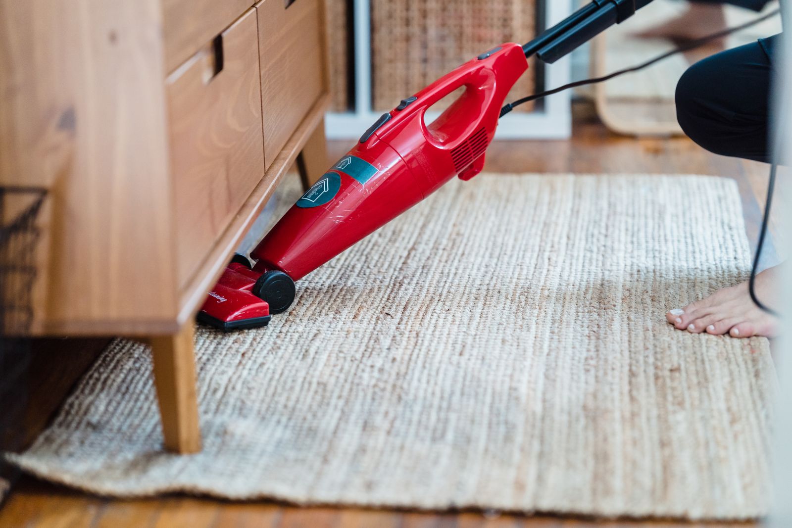 Person vacuuming under a side cabinet reaching a tight space