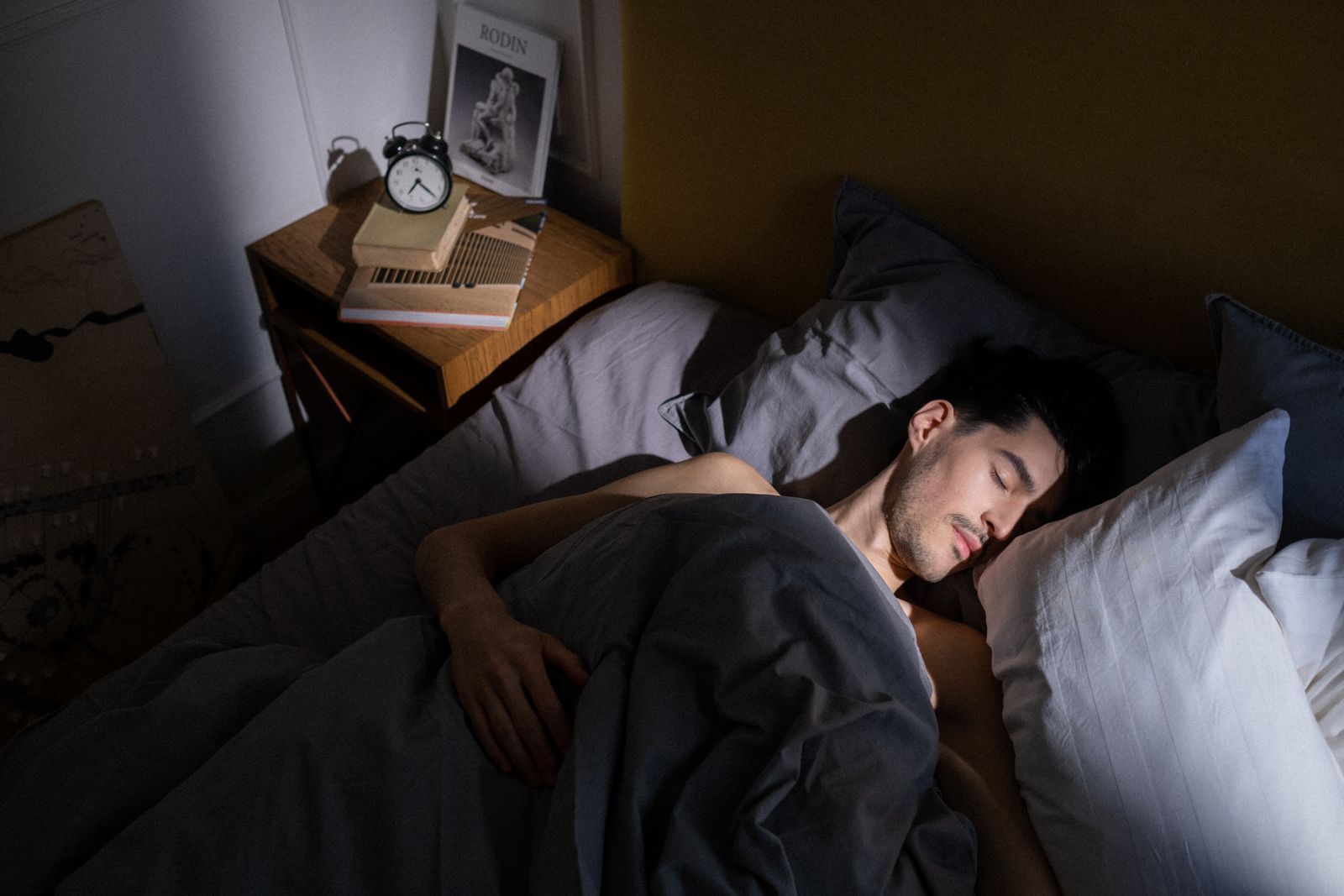 Person sleeping peacefully on a bed in an airy bright bedroom