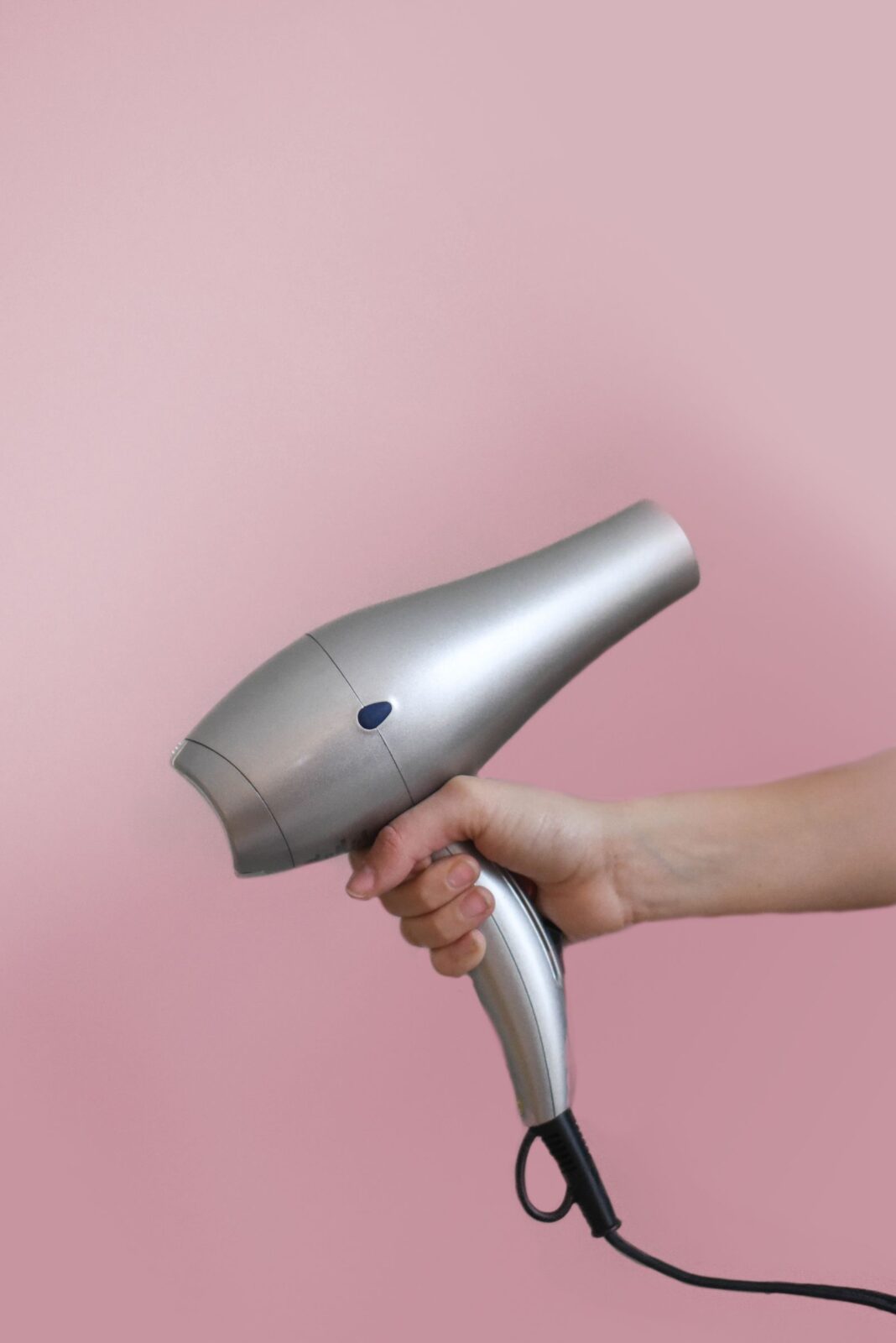 A person holding a grey hair dryer