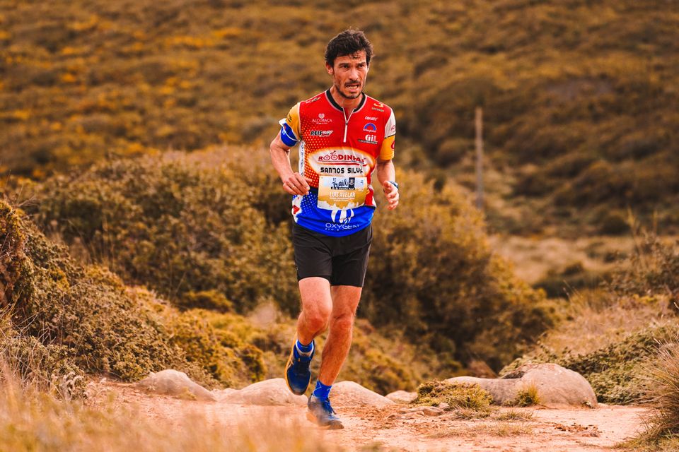 Focused athlete running through rugged terrain during a trail race
