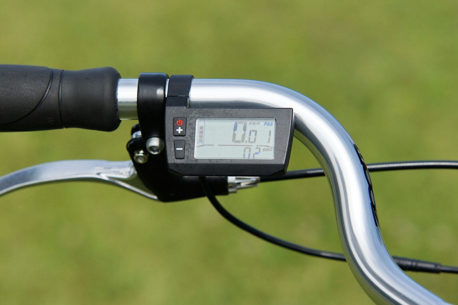 A close-up view of a digital speedometer display mounted on bicycle handlebars outdoors