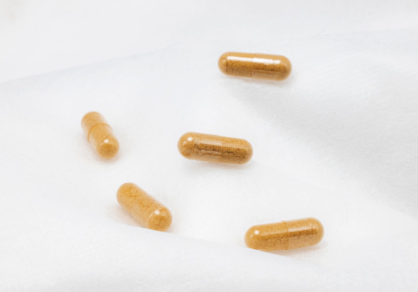 Close-up of brown supplement capsules arranged on a white surface