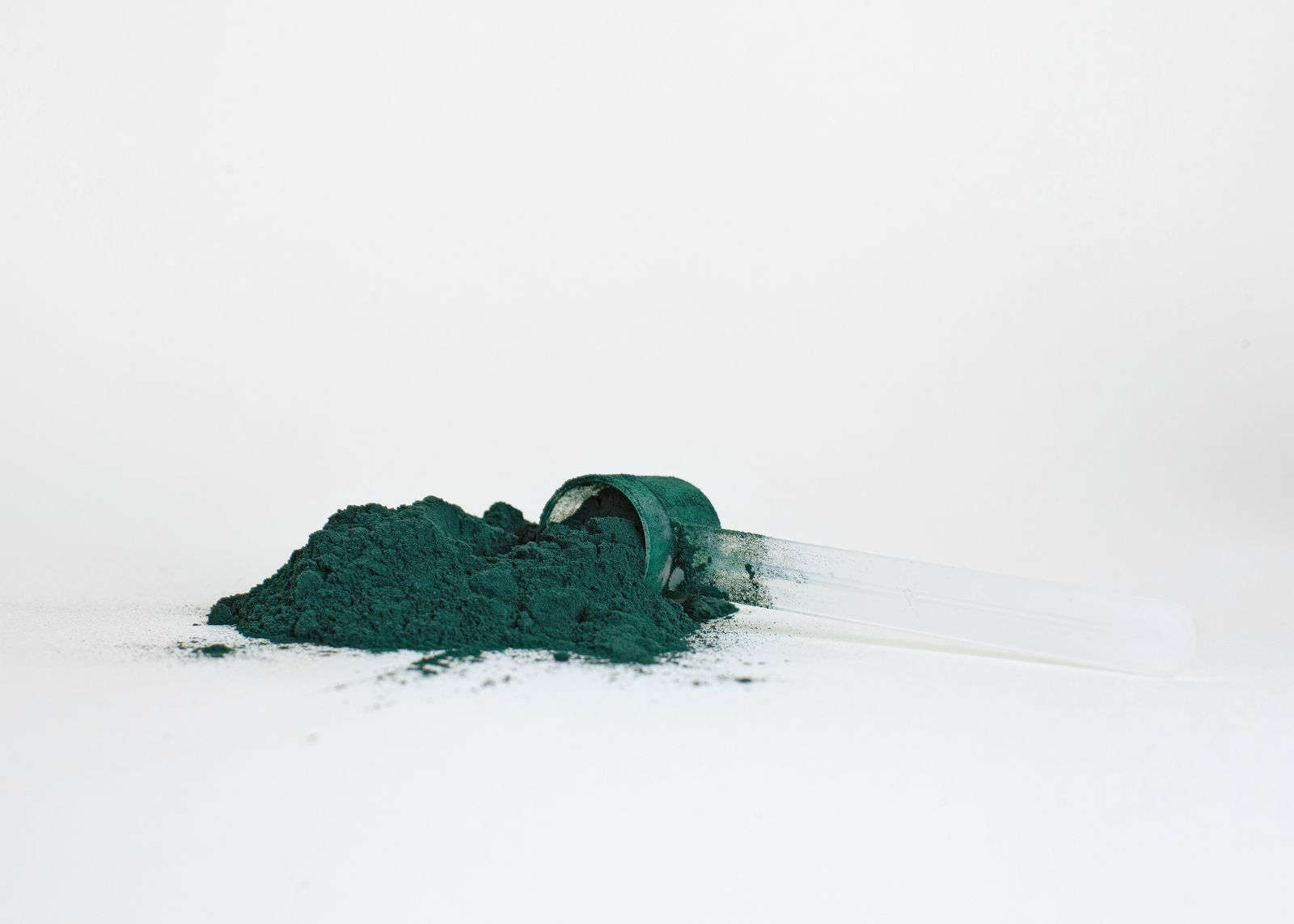 A measuring scoop of powder poised over a container, ready to be mixed into water