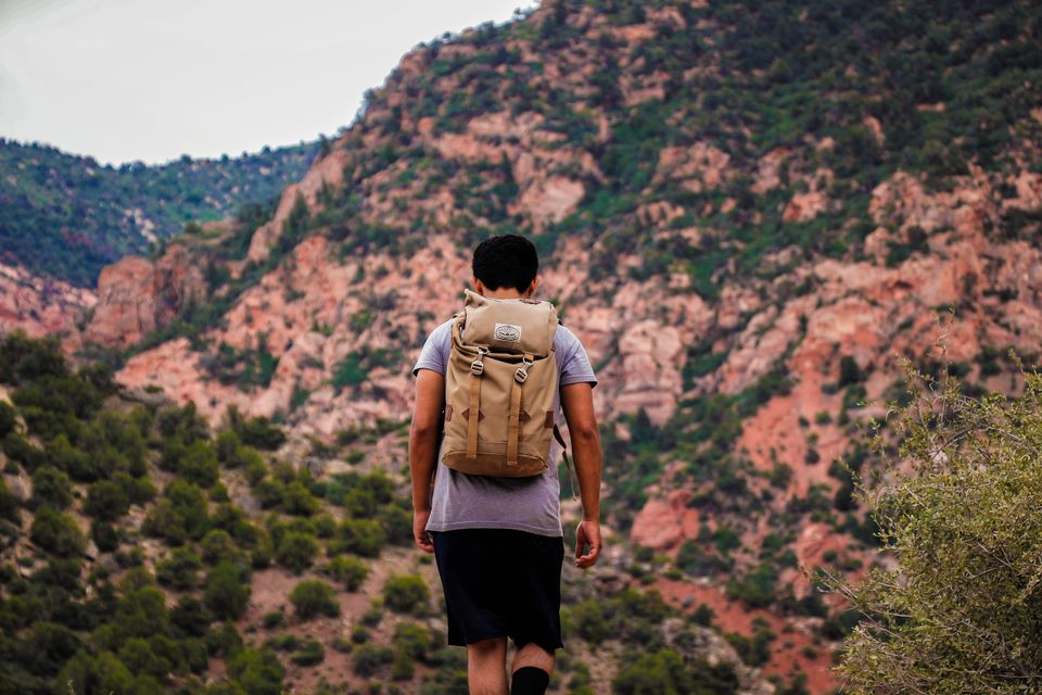 A lone backpacker hikes a mountain trail surrounded by nature