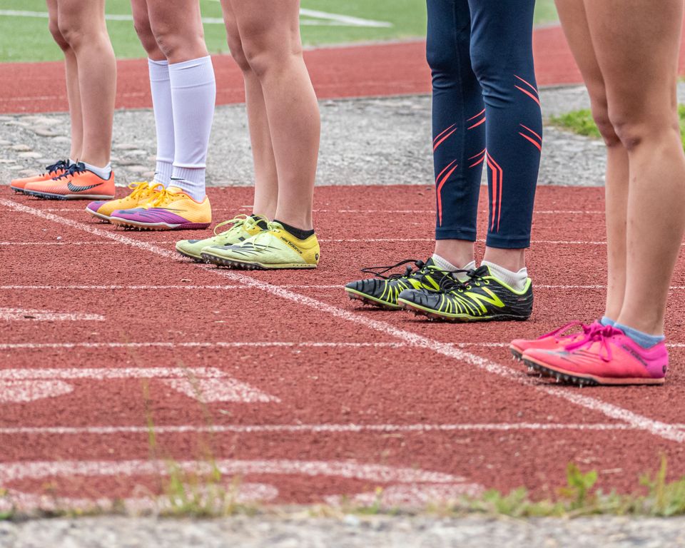 Group of runners preparing to start a race with vibrant footwear on a track