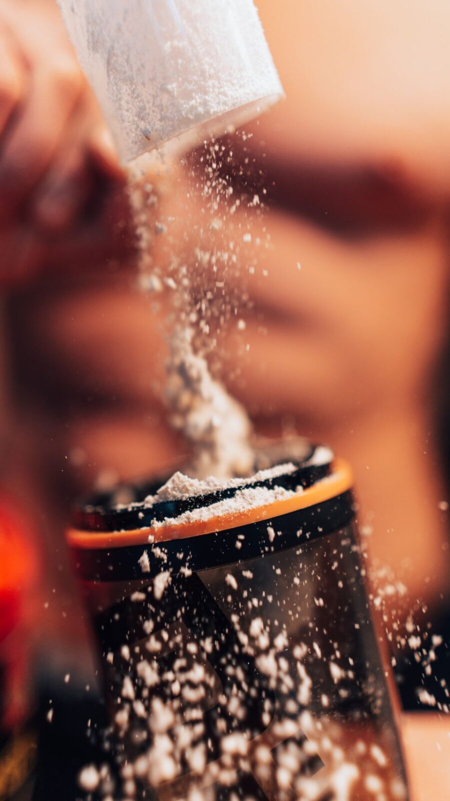 Protein powder being scooped into a shaker bottle