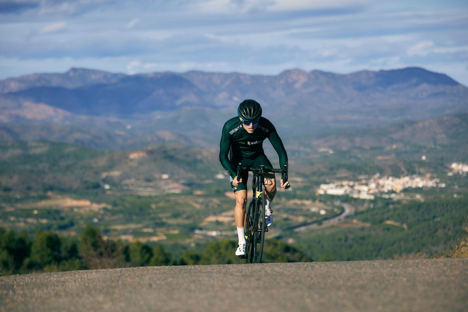 A focused cyclist in sportswear riding a road bike uphill on a mountain road