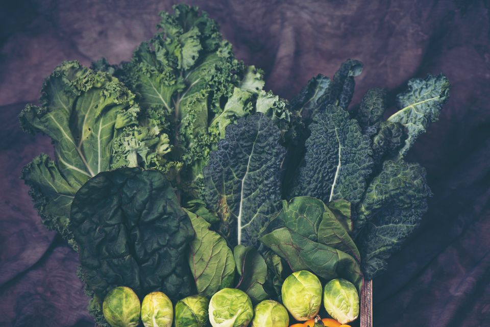 Fresh kale and Brussels sprouts arranged together, showing whole leafy green vegetables