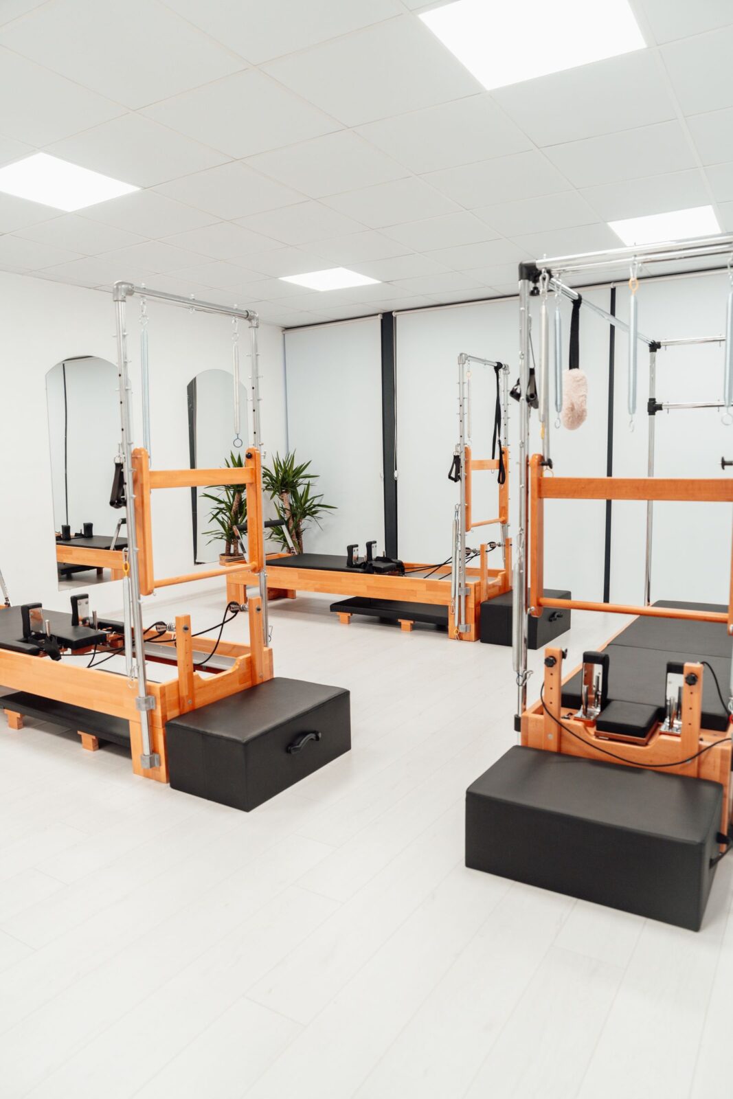 Several Pilates reformer machines arranged in a bright room