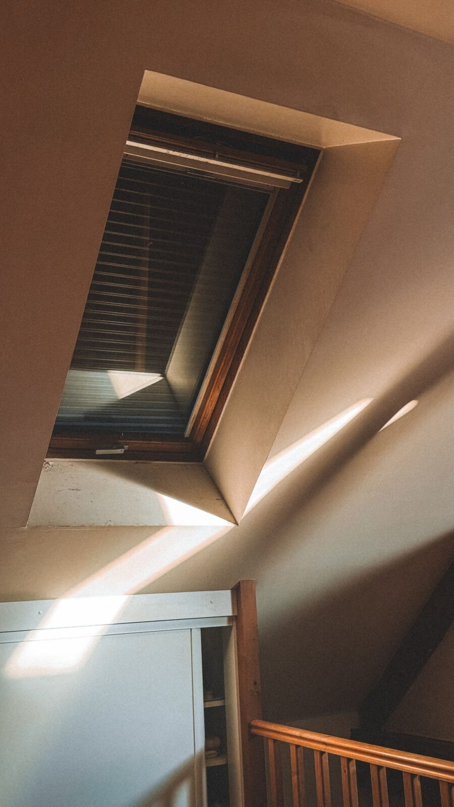 Sunlit attic space with wooden beams, the kind of space where an attic fan or whole-house fan draws hot air out of a home