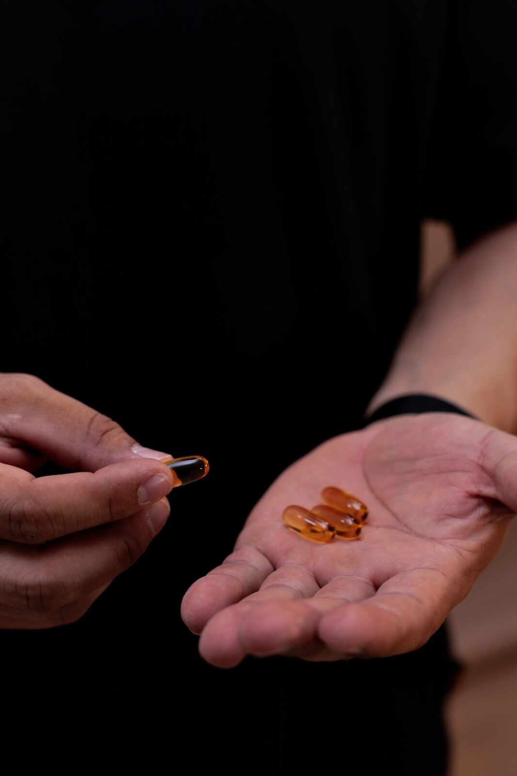 Amber-colored softgel capsules resting in an open palm