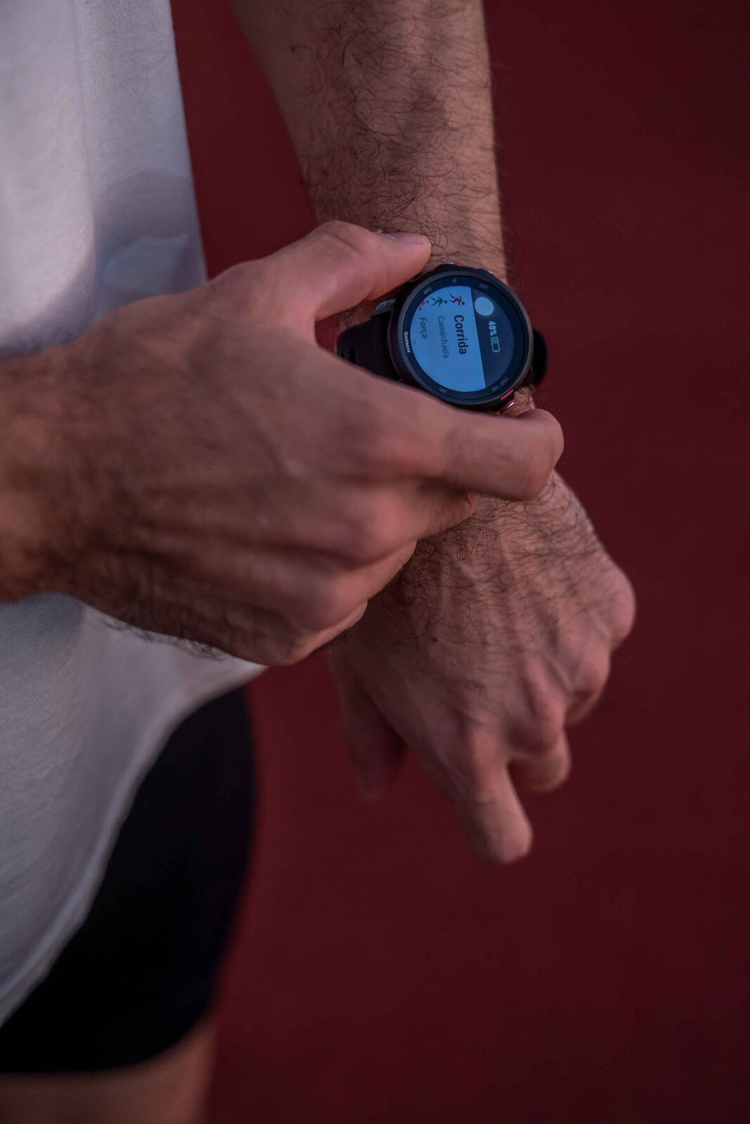 A male runner checking his smartwatch on an outdoor track after finishing a run