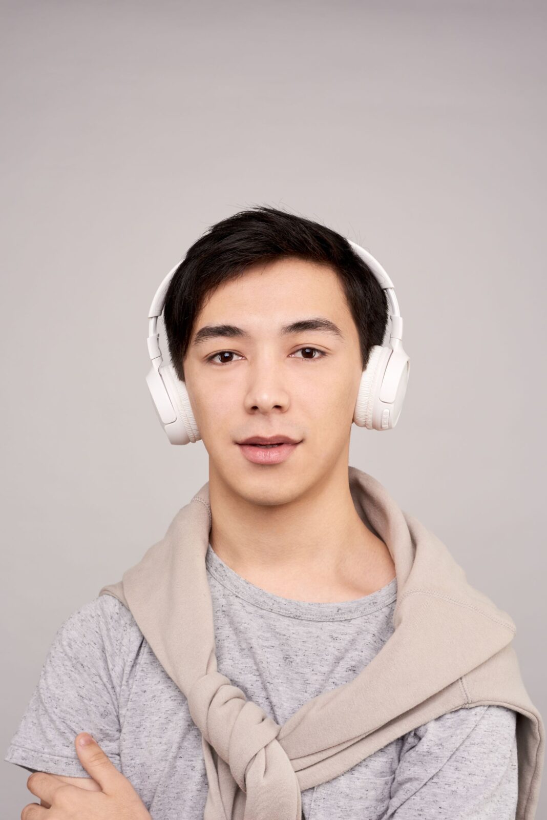 A man wearing white over-ear headphones looking at the camera