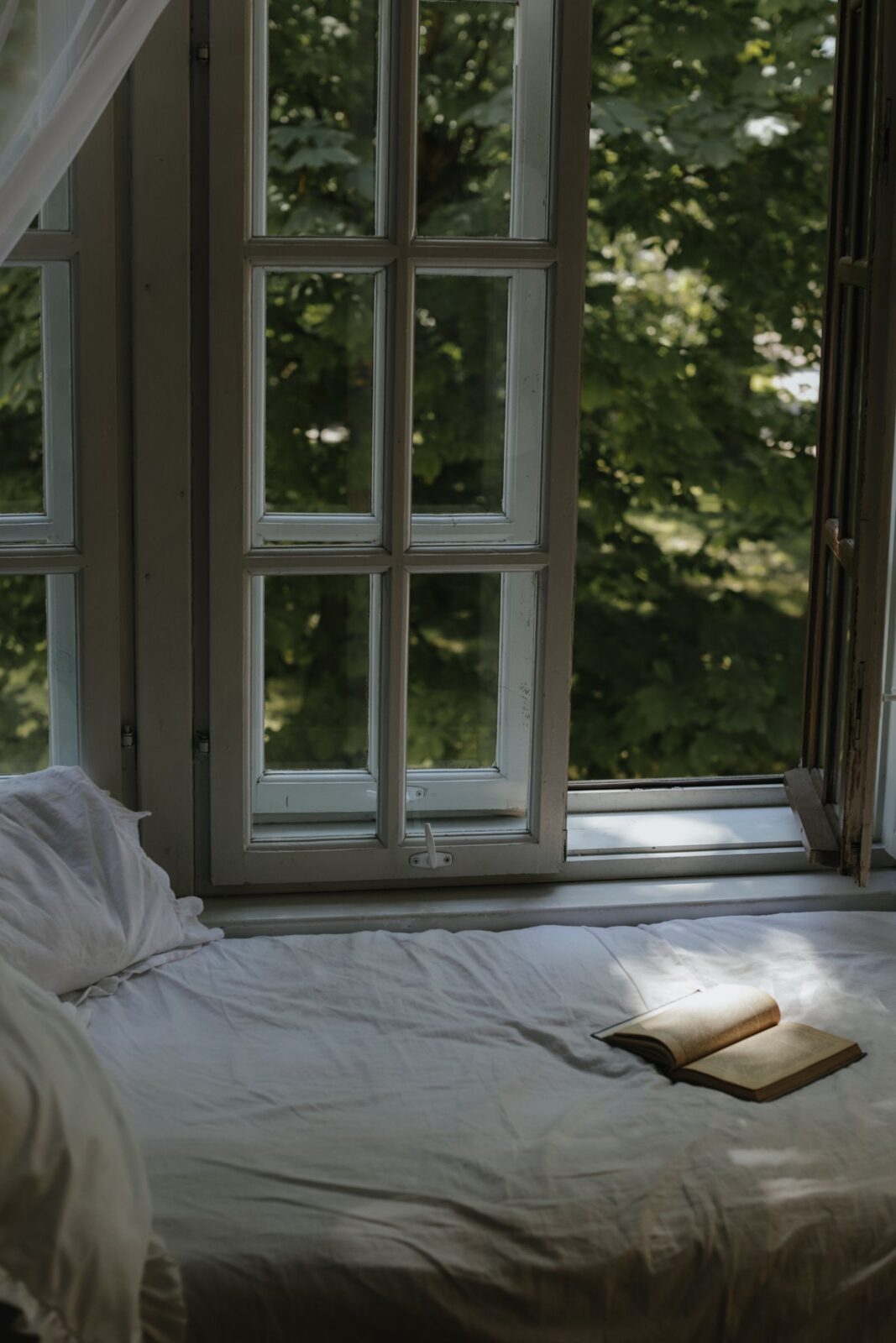 Cozy bedroom with an open window letting in daylight and fresh air, the setup a window fan is designed to cool