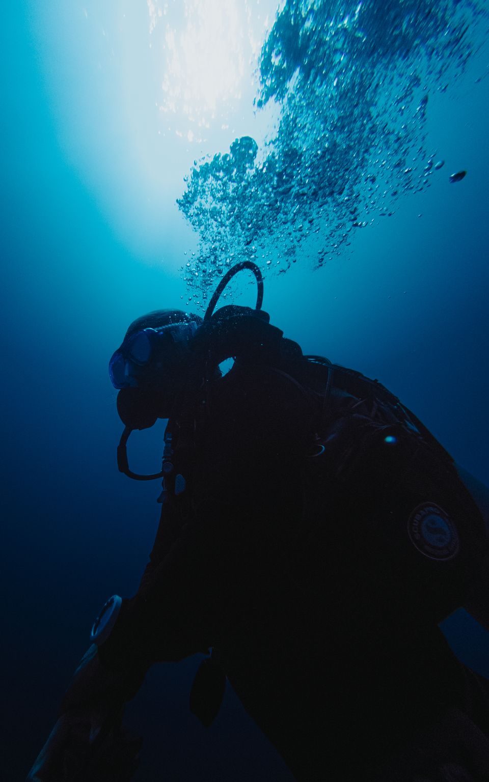 Scuba diver exploring the deep blue ocean beneath sunlight