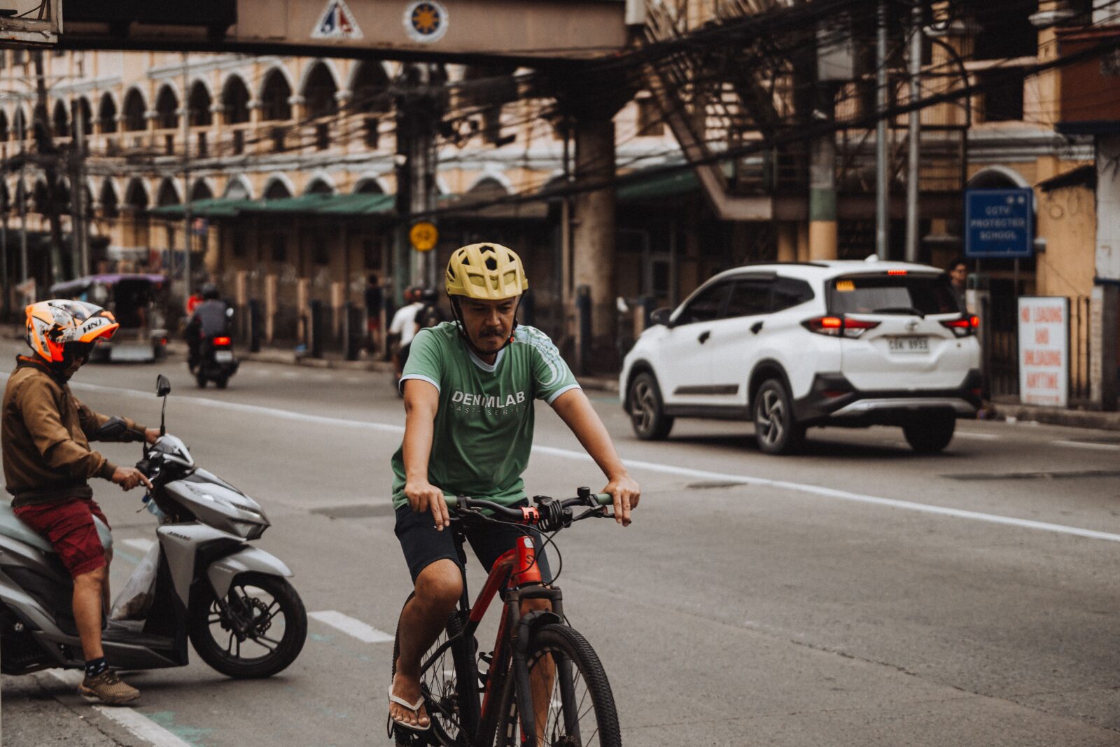 A cyclist wearing a helmet rides alongside city traffic on a busy urban street