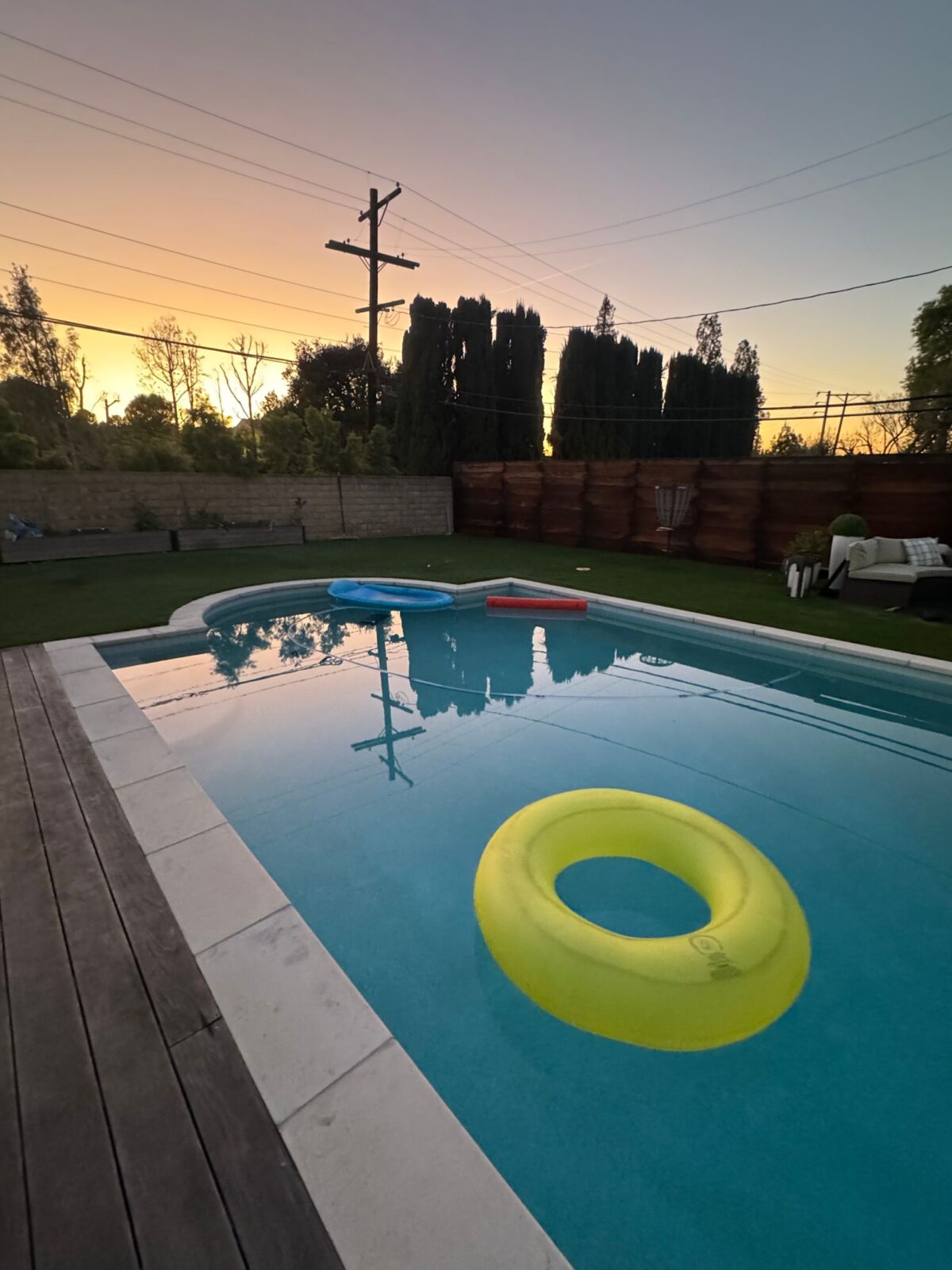 Family pool floaties in a backyard swimming pool at sunset