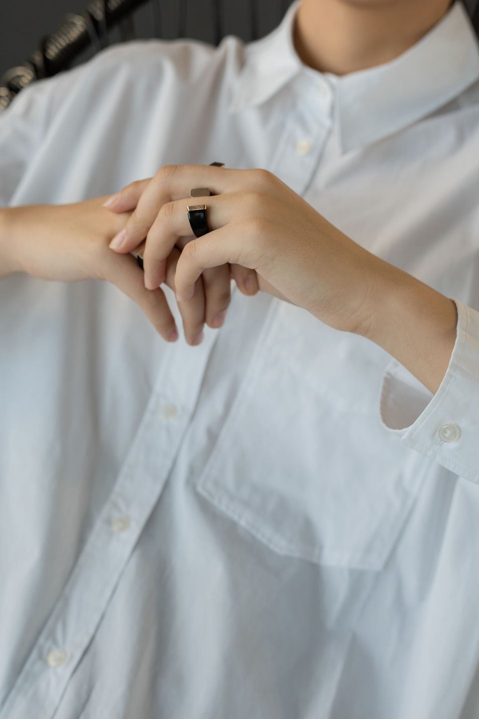 Close-up of adult hands wearing rings, dressed in a white buttoned shirt