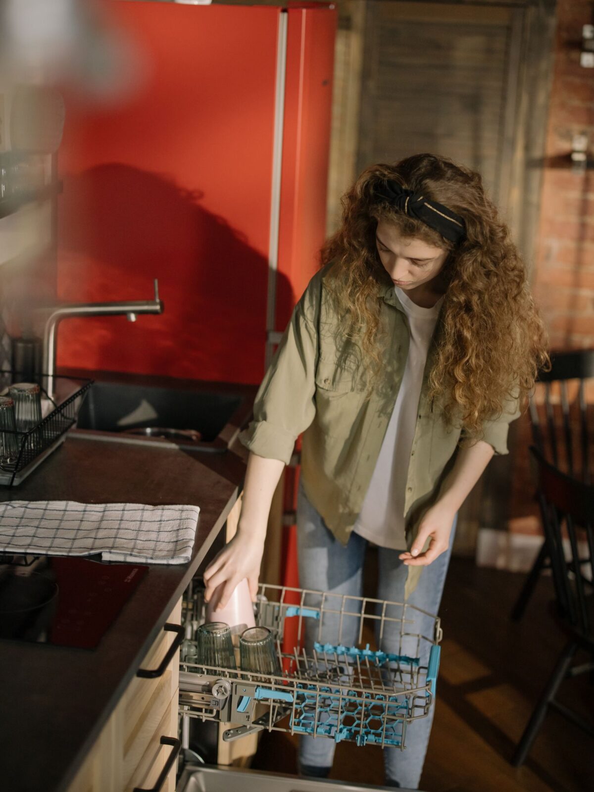 Person loading dishes into a dishwasher in a bright kitchen