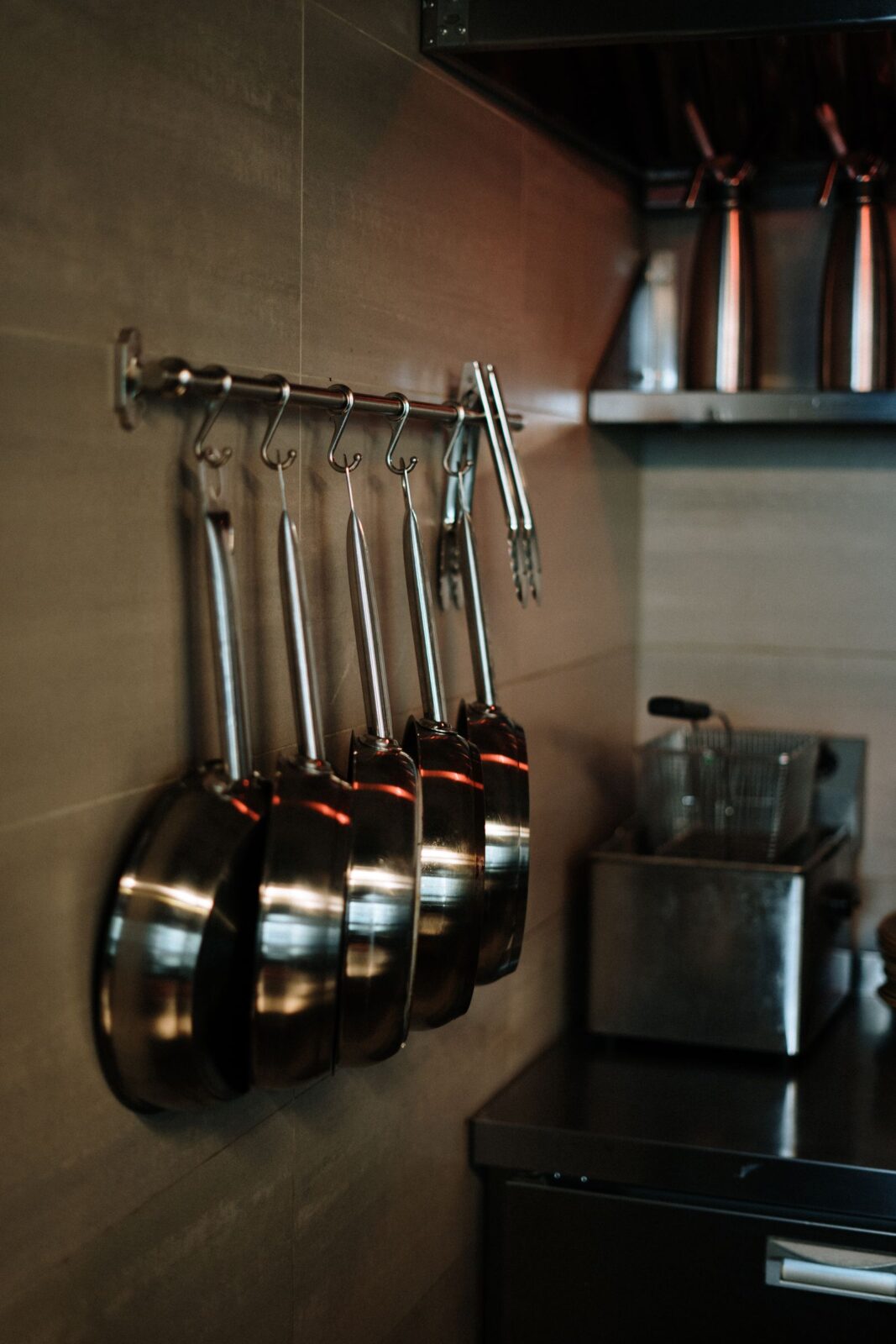 Stainless steel skillets hanging on a kitchen rack