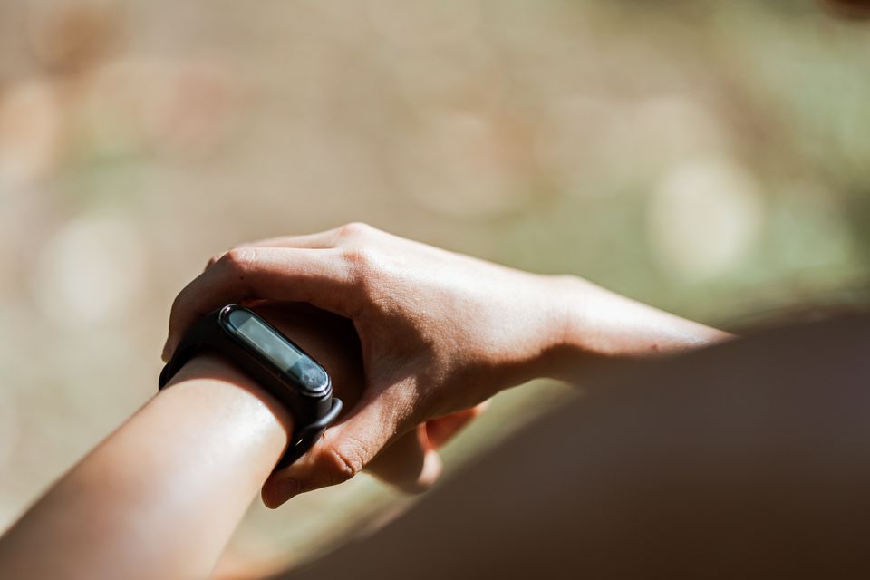 Overhead view of a person wearing a wrist band with a small display outdoors