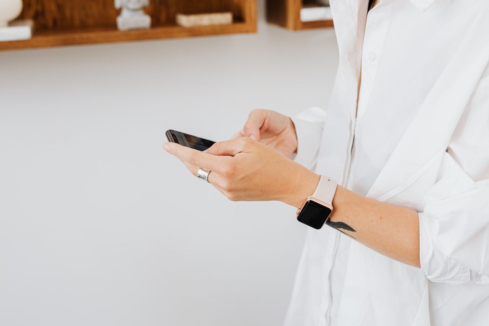 Close-up of person in white shirt using smartphone, wearing a smartwatch