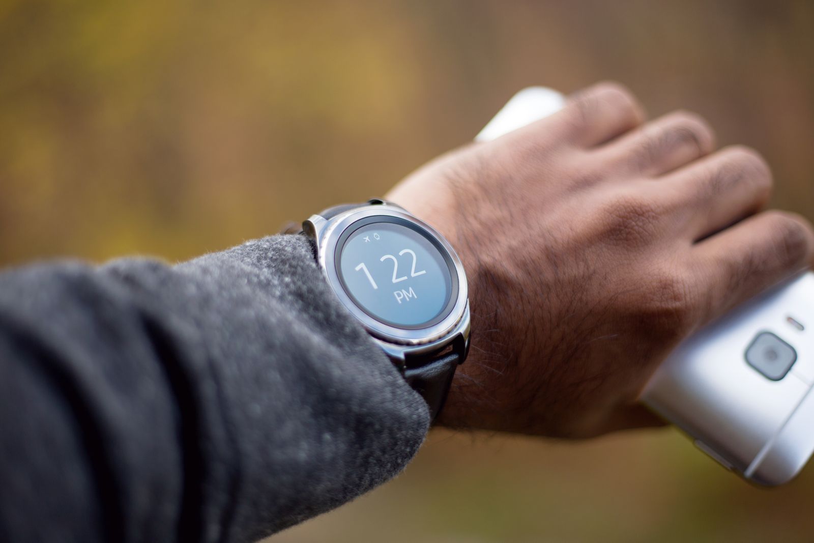 Close-up of a smartwatch on a man's wrist holding a mobile phone