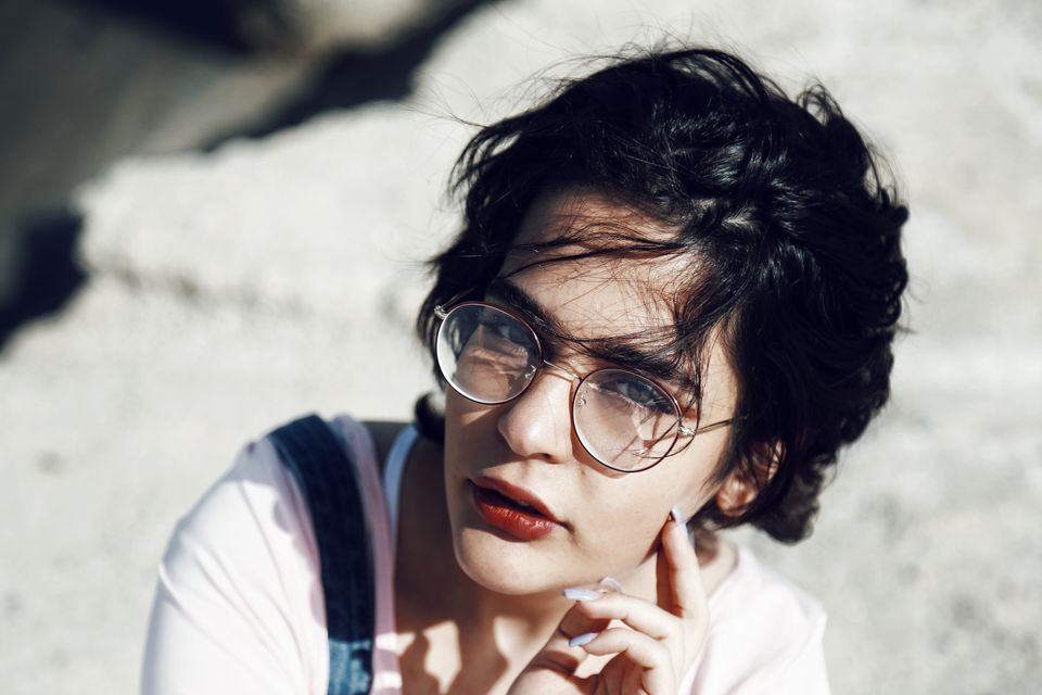 Stylish portrait of a young woman with glasses and short hair outdoors