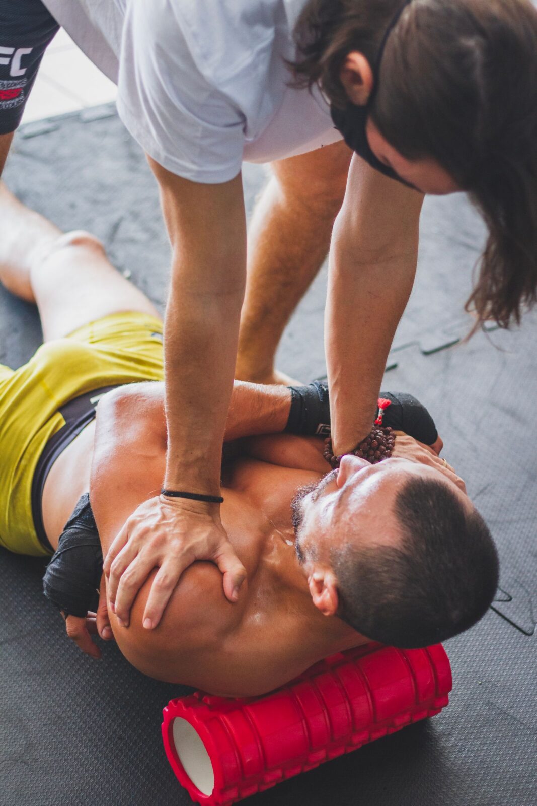 Trainer helping an athlete stretch and roll on a foam roller