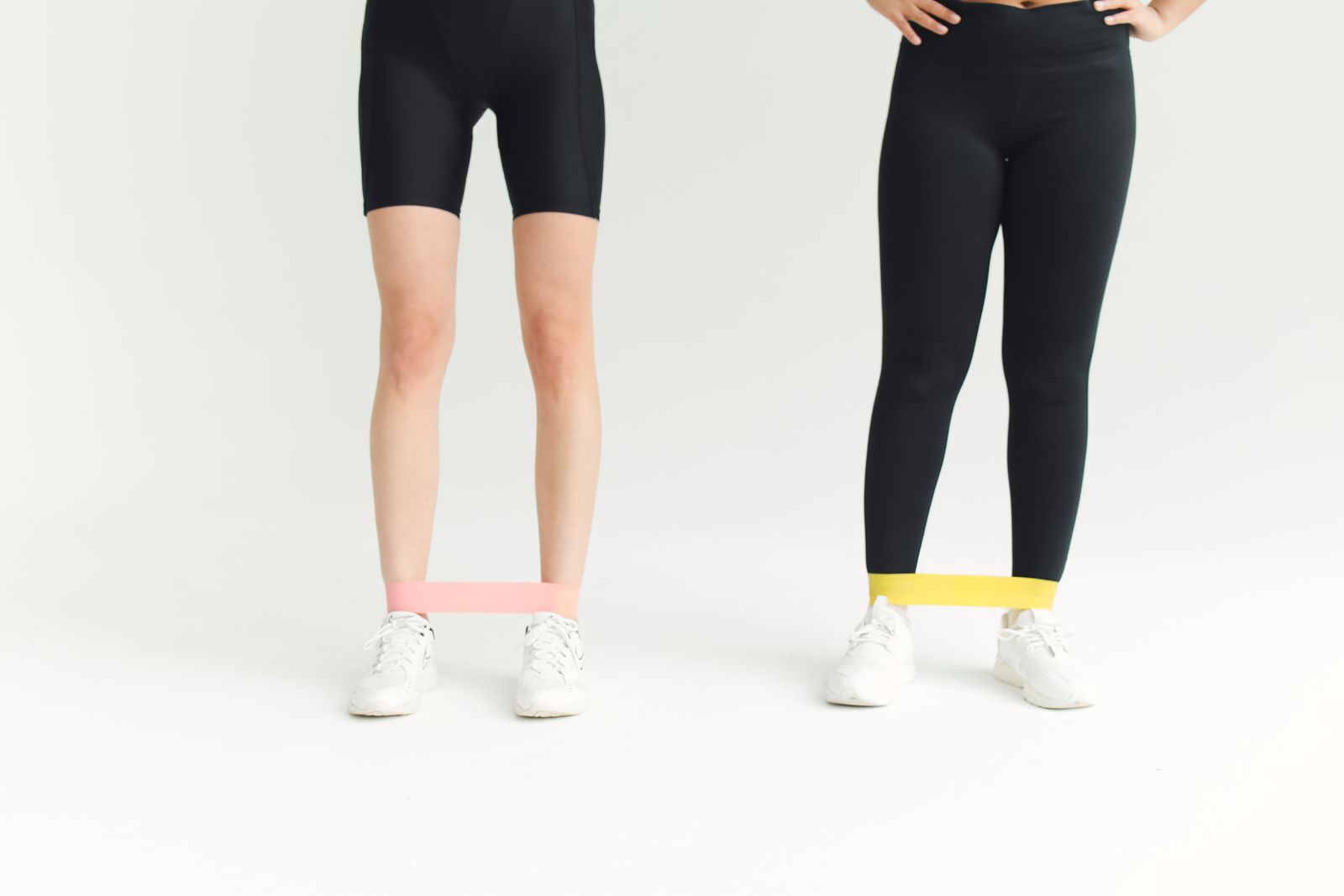 Two people using loop resistance bands around their shins during a lower-body workout