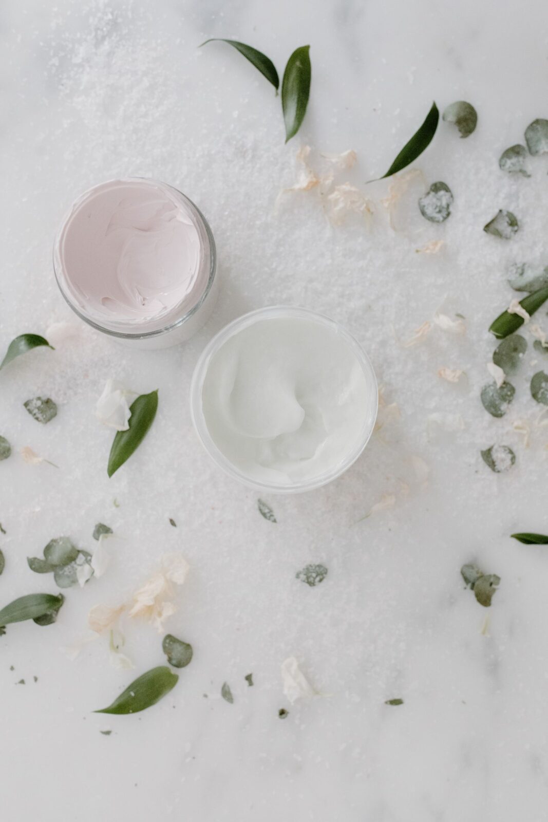 Overhead view of skincare cream jars on a marble surface
