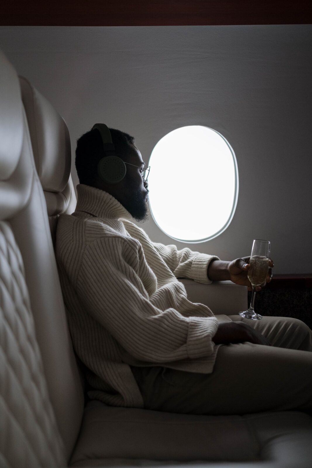 A man wearing over-ear headphones looking out an airplane window