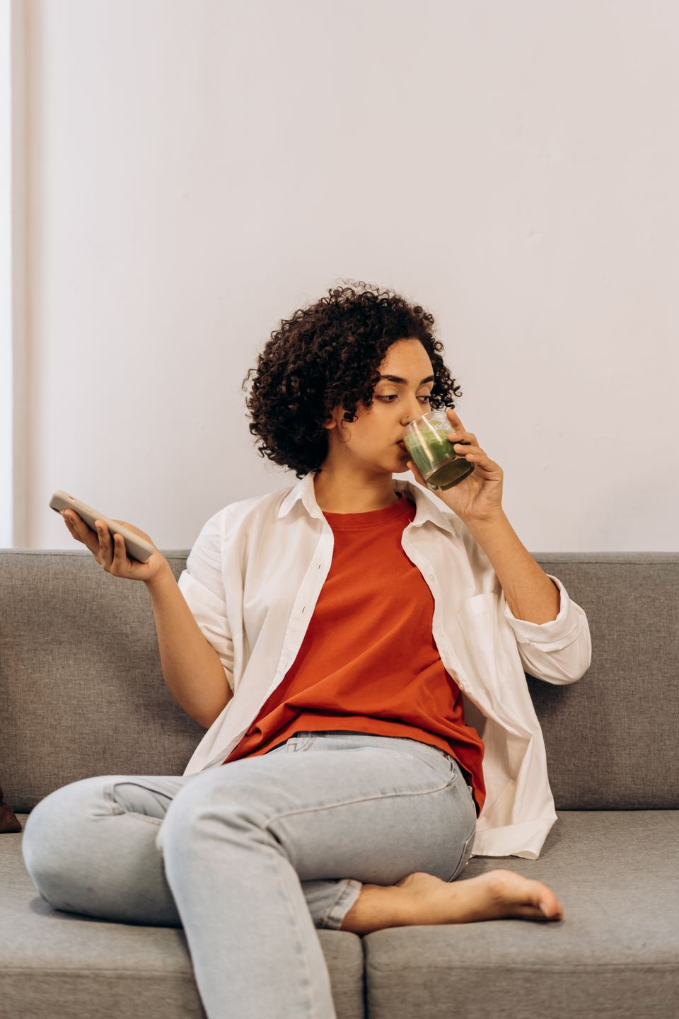Woman relaxing at home while drinking a green smoothie from a glass