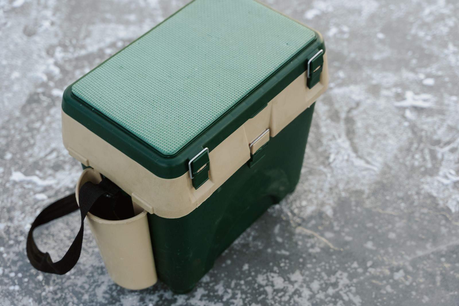A hard cooler sitting on a frozen, snowy outdoor surface