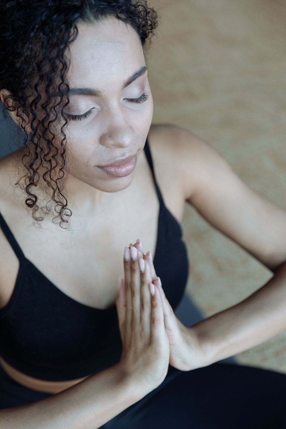 Close-up of a woman meditating indoors with eyes closed and hands together