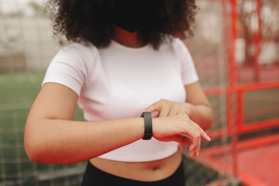 Young woman wearing a fitness tracker, checking time in an outdoor sports area