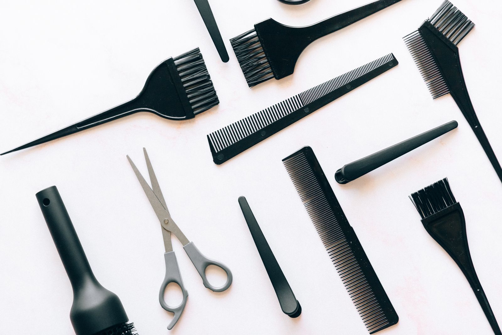 Flat lay of black hair styling tools including brushes, combs, and clips